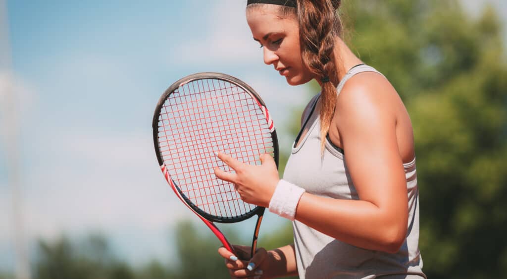 girl adjusting tennis strings